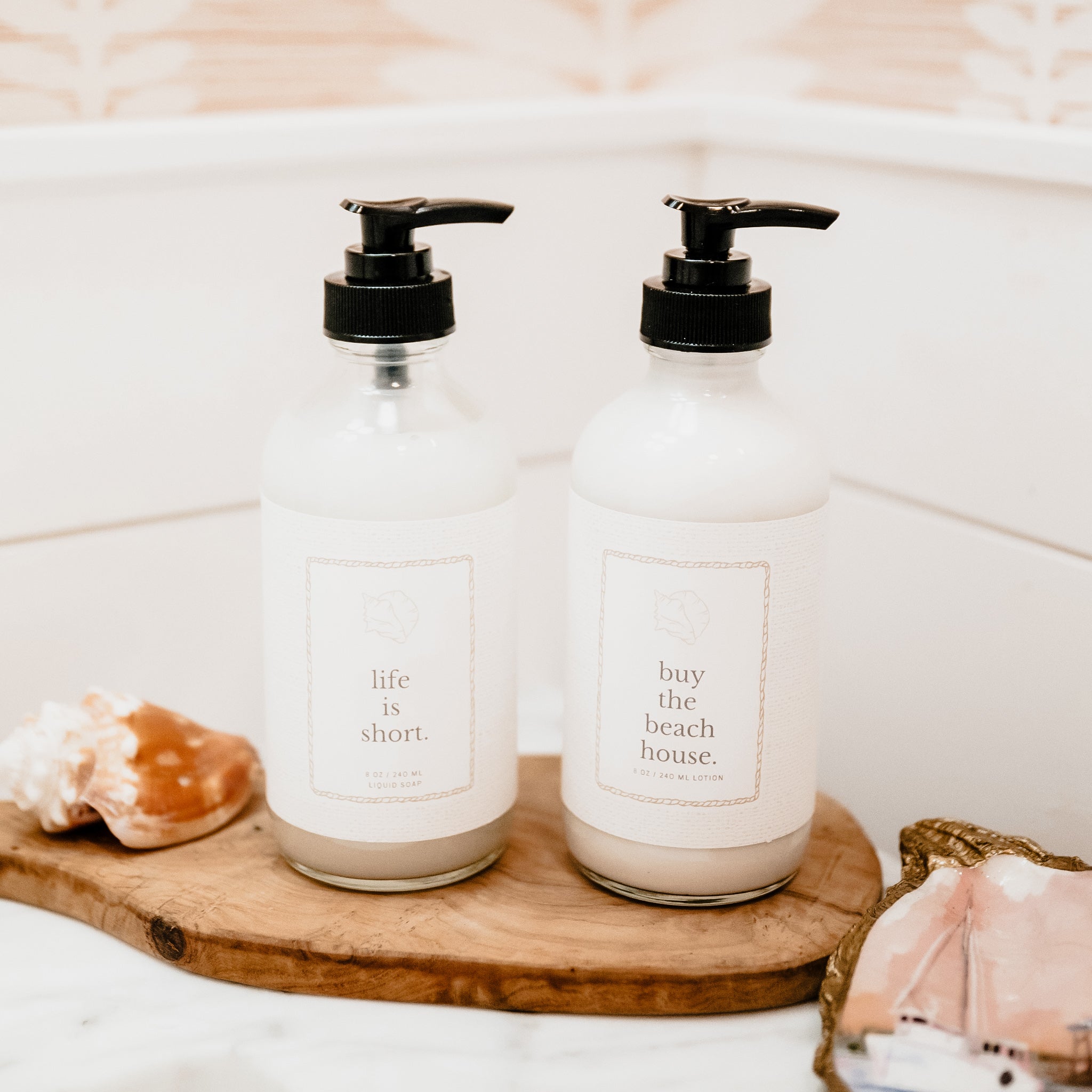 Two bottles with pump dispensers on a wooden tray in a bathroom setting.
