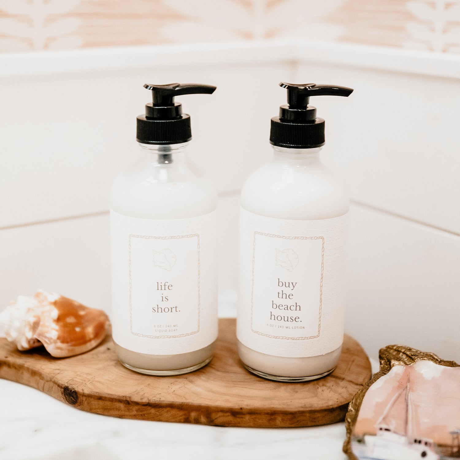 Two bottles with pump dispensers on a wooden tray in a bathroom setting.