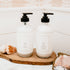 Two bottles with pump dispensers on a wooden tray in a bathroom setting.