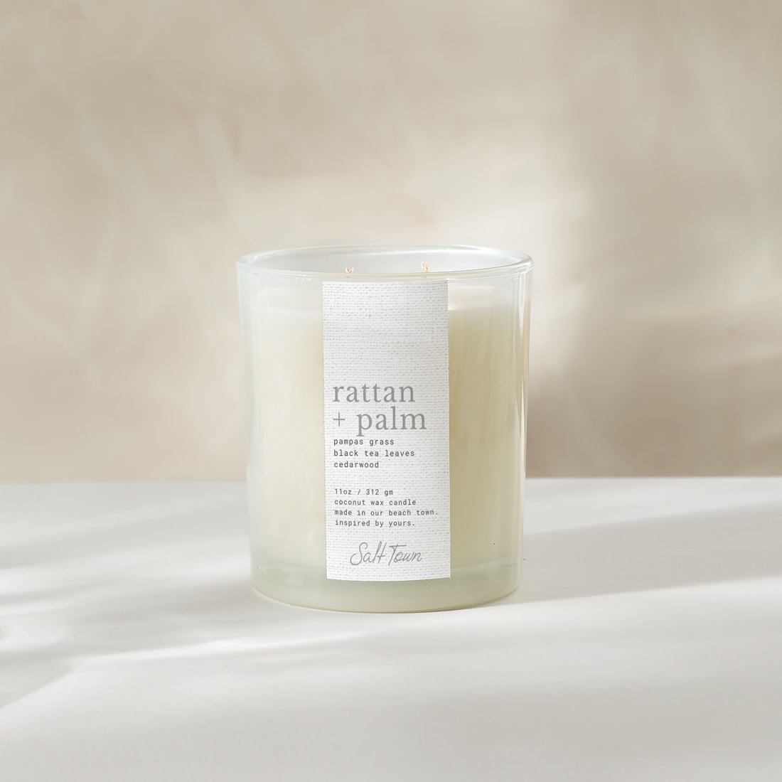 Rattan Palm candle on a white surface with a neutral background.